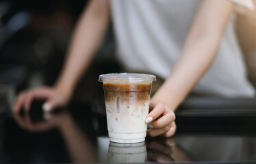 Closeup shot of  woman holding a plastic cup of coffee at cafe