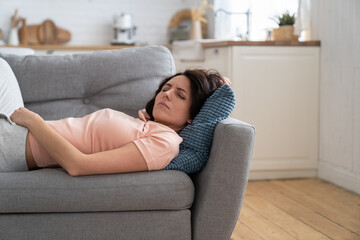 Young woman with closed eyes lying on pillow, resting, trying to sleep in uncomfortable pose on...