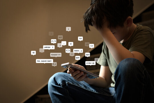 Cyberbullying - social media harassment concept. Young asian preteen, teenager boy looking at his smartphone feeling frustrated after reading bad comments. Text emoticons. Bully, Teen mental health