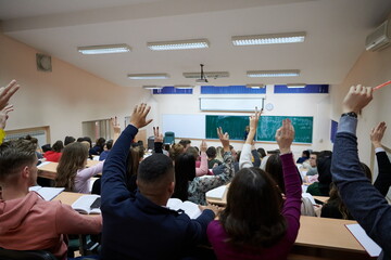 Fototapeta na wymiar Raised hands and arms of large group of people in class room