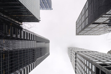 City skyscrapers bottom view against gray sky. Low wide angle shot, from ground. Modern business district concept. Copy space