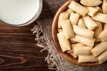 Breakfast dried pads with glass of milk on dark wooden background.