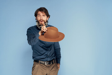 handsome man in a hat flowers in a beard stylish clothes blue background