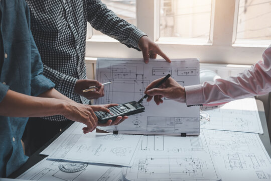 Close-up architect brainstorming together Point at the blueprint calculator at the office.