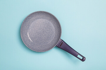 Blue frying pan on blue background. Simple new empty Non-stick Frying Pan with purple handle...