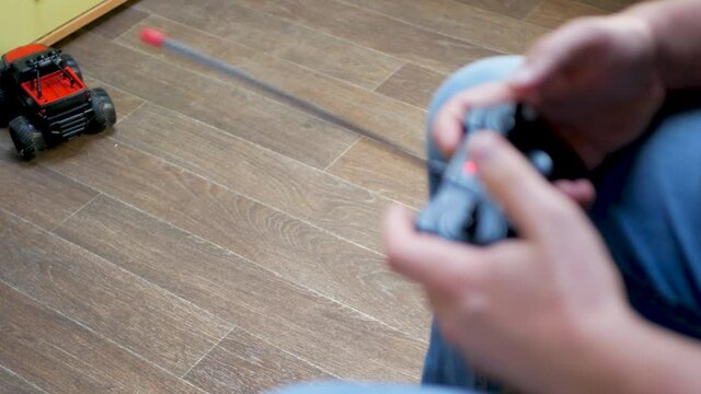 Controlling toy car with joystick remote control. Relaxation at work or home concept. Radio-controlled car. How to ride toy car with remote control, birthday gift