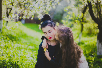 Happy mother's day. Little girl hugs her mother in the spring cherry garden. Portrait of happy mother and daughter among white flowers trees. Family values. Motherhood. Mom and child in blooming park.