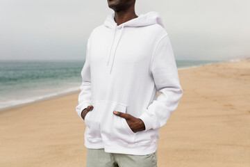 Cool African American man in white hoodie at a beach winter shoot