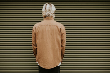 Blonde man in brown shirt jacket with design space rear view