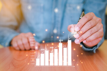 Businessman plans business growth in 2021. Concepts of finance, marketing, Sales increase and Business Growth Planning with technology. Analysis using graphs
