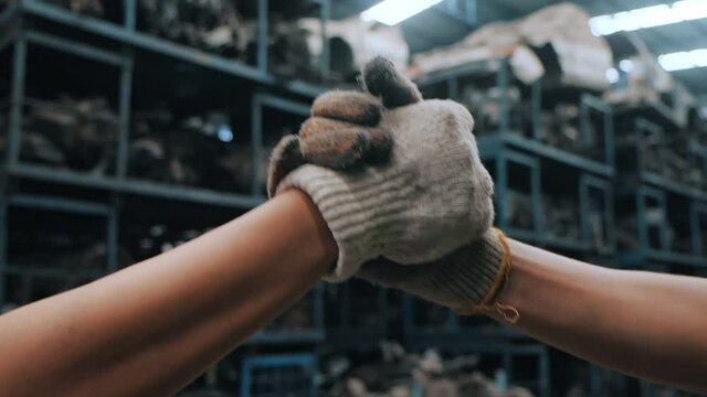 Close up of Handshake two workers or high five wearing working gloves at industrial factory background, Teamwork partnership industrial concept. Sensitive focus, Slow motion.