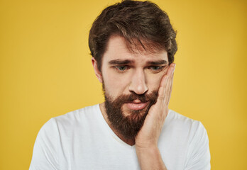 sad man on a yellow background in a white t-shirt beard model