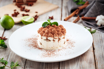 Side view on tiramisu dessert with mint on a white plate