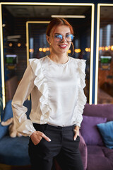 Joyful young woman standing in modern office