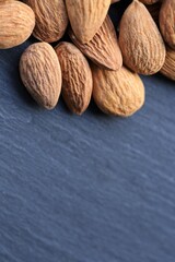 Almond nut. Raw almonds nuts  on black slate background.Nuts and seeds  closeup.Tasty snack. Healthy fats.