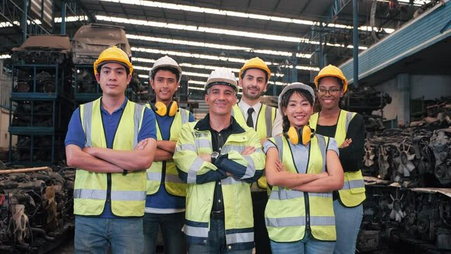 Group portrait of multiethnic industrial workers team consist of technicians, engineers, mechanic wearing helmet uniform looking camera in used auto parts factory. Industrial workers concept