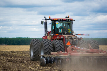 red tractor in a field rear view, tractor with a plow on an agricultural field. big red tractor working in the field, harvesting, business, agriculture. August, Kiev region