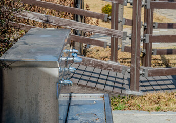 Closeup of stainless steel water basin with four faucets in public park.