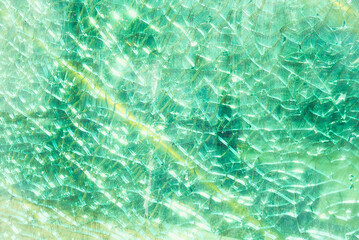 Close-up of a pastel green colored broken fragmented glass window shield, with a yellow line