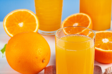 Glass of orange juice and cut oranges on table