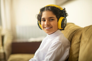 Young Arabian boy listening to music on headphones at home