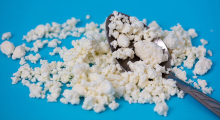 Milk curd in a spoon on a blue background.