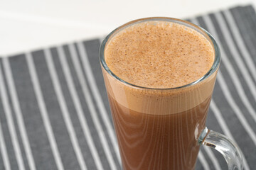 Glass cup of cocoa drink on white wooden table