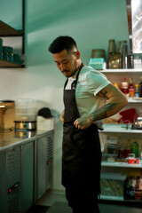 Asian man in apron stands in the kitchen