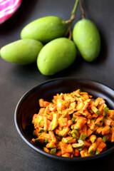Green mango salad. Raw mango instant pickle. also known as kairichi koshimbir in Marathi. copy space over black background. Chopped raw green mangos mixed with salt, red chilli powder and sugar. 