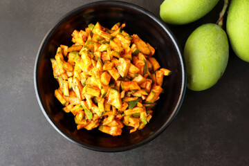 Green mango salad. Raw mango instant pickle. also known as kairichi koshimbir in Marathi. copy space over black background. Chopped raw green mangos mixed with salt, red chilli powder and sugar. 