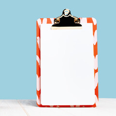 Front view of elegant red notepad clip board mock up on blue. Copy space for announcement