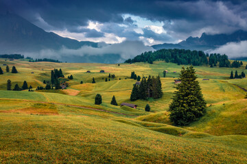 Dramatic summer scenery. Low overcast view of Compaccio village, Seiser Alm or Alpe di Siusi location, Bolzano province, Dolomite Alps, South Tyrol, Italy, Europe. Traveling concept background..