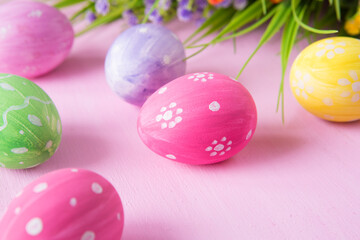 Easter eggs with wild flowers on a wooden pink table background