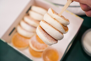 Mini soufflé pancake stack. A mini fluffy pancake on a Skewer with pancake box background.