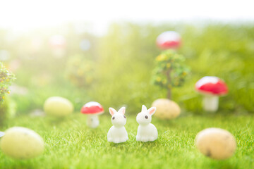 Little Easter bunny toys and Easter eggs on green grass. Fairy tale