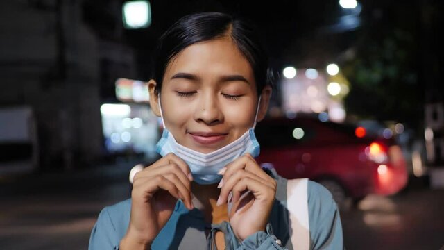 Asian woman wearing a dustproof mask on the street at night.
