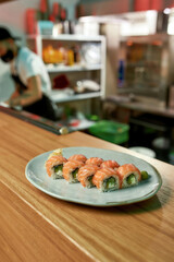Sushi rolls with salmon, avocado and cheese laid out on a white plate