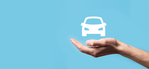 Male hand holding car auto icon on blue background. Wide banner composition.Car automobile insurance and collision damage waiver concepts