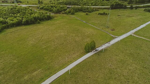 Shooting from the air from a distance of a white carriage pulled by a horse. Shooting is done in motion