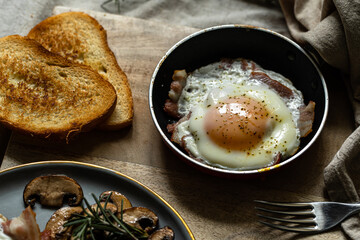 Breakfast with fried egg(sunny side up) with bacon, grilled with rosemary mushrooms and toast with cream cheese. 