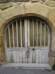 Fototapeta na wymiar old wooden arch door of a troglodyte cave in a limestone wall