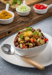 black gram or kala chana chaat with boiled potato, onion, tomato with a dash of lemon juice served on a white bowl