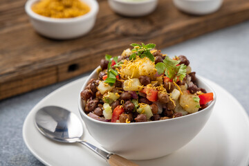 black gram or kala chana chaat with boiled potato, onion, tomato with a dash of lemon juice served on a white bowl