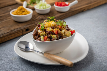 black gram or kala chana chaat with boiled potato, onion, tomato with a dash of lemon juice served on a white bowl