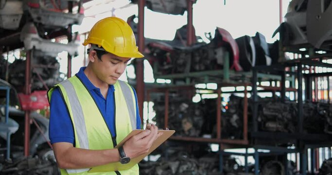 Asian man workers technical with safety suit helmet walking around car industry checking stock of used auto parts in factory industrial