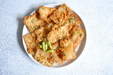 a plate of fried crispy tempeh served with fresh chili 