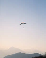 Paragliding at sunset over the mountains, Italy