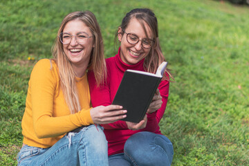 Two women enjoying reading a book in a park