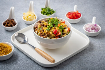 black gram or kala chana chaat with boiled potato, onion, tomato with a dash of lemon juice served on a white bowl