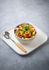 black gram or kala chana chaat with boiled potato, onion, tomato with a dash of lemon juice served on a white bowl